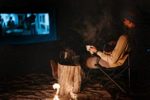 Man watching a movie beside a fire